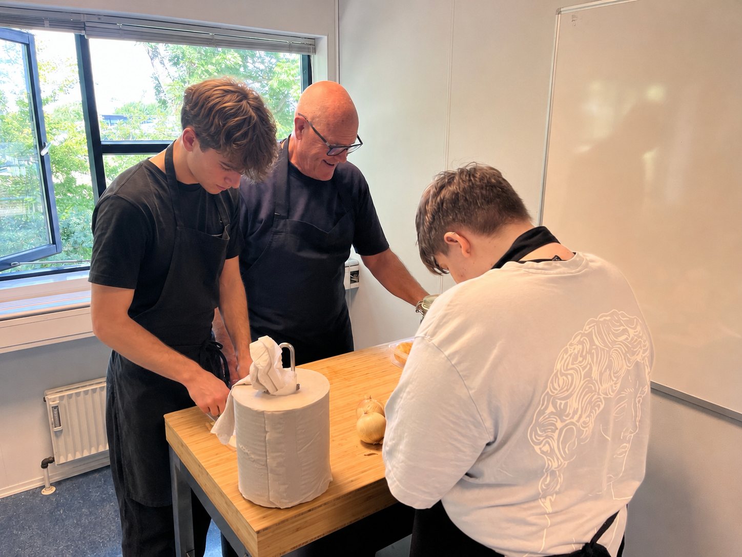 Unge og en underviser arbejder sammen om en køkkenopgave